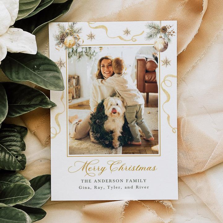 Christmas card with a photo of a family and dog, surrounded by greenery and fabric.